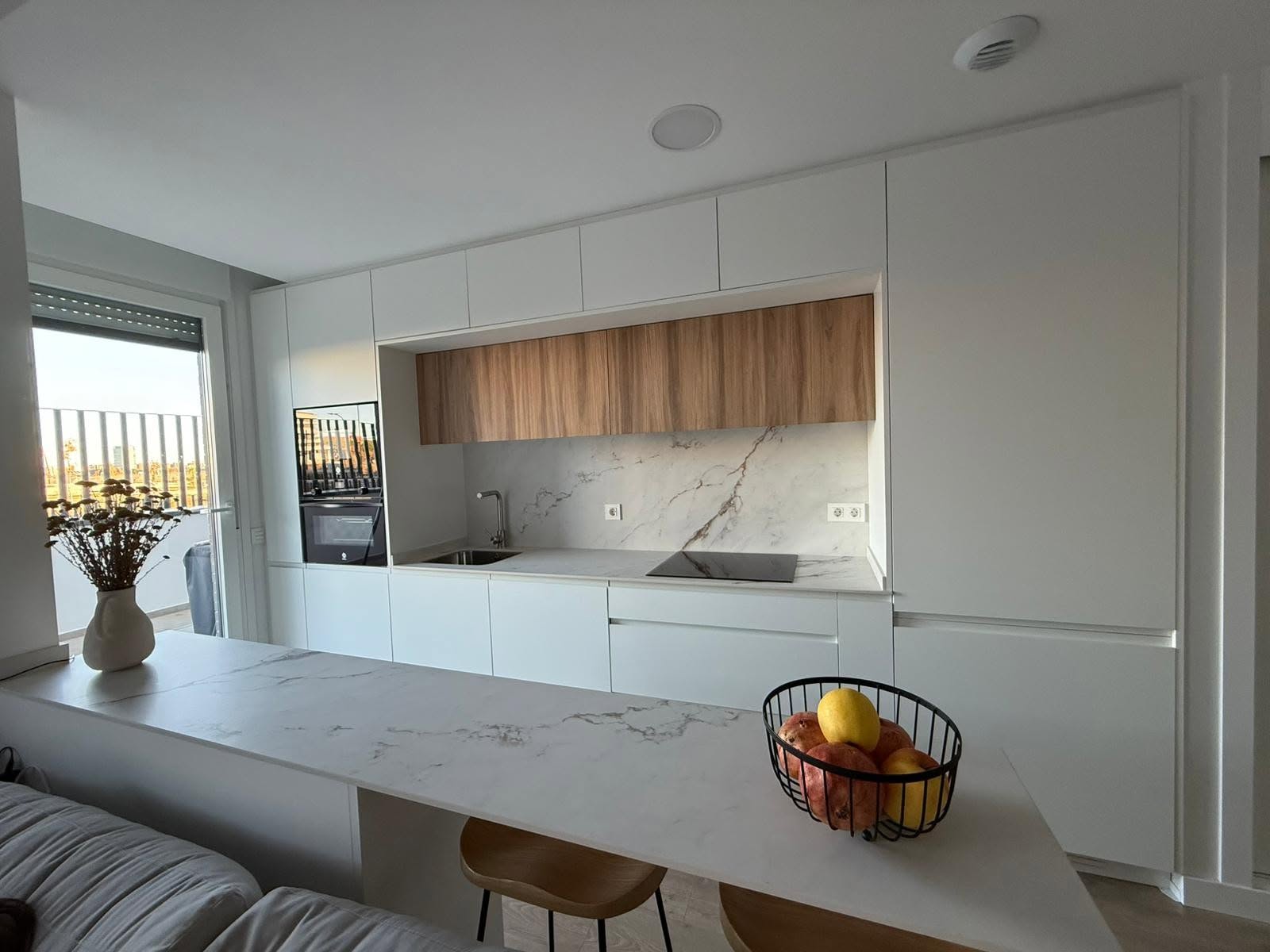 Cocina terminada con muebles en blanco con una isla central así como partes de madera